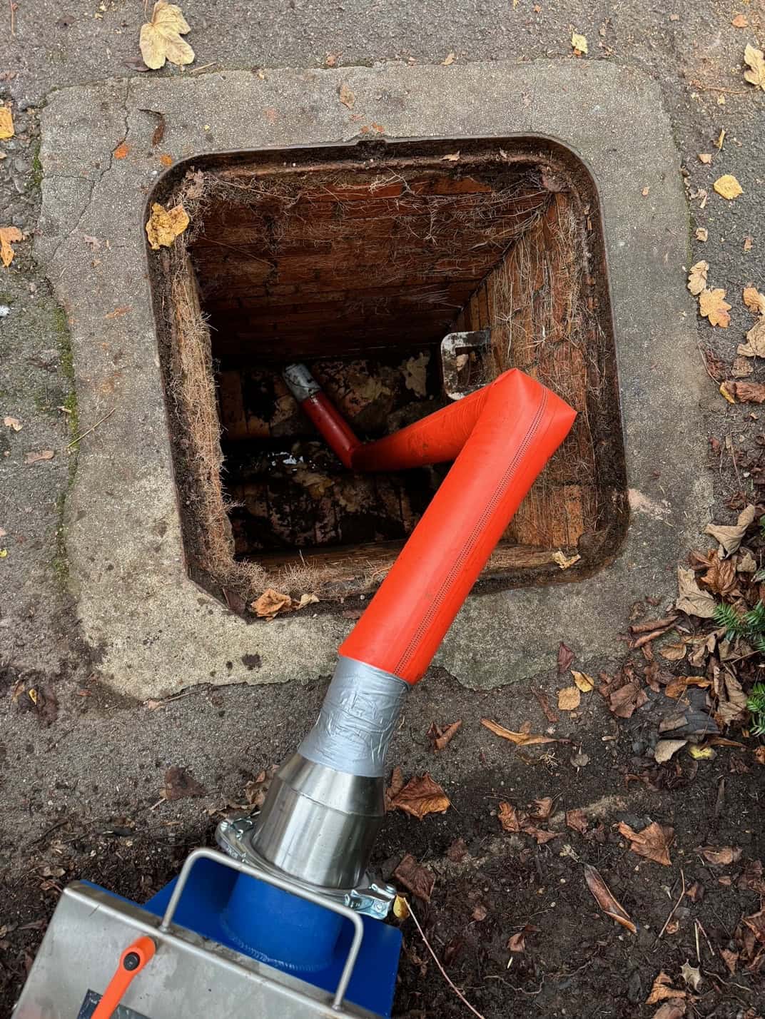 Close-up of drain inspection with pipe relining equipment in an open manhole.