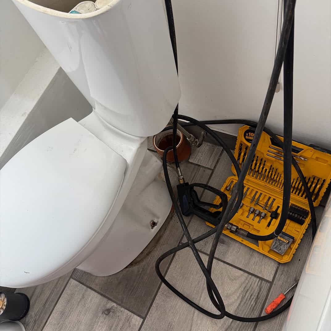 Plumbing tools for blocked drain repair near toilet.