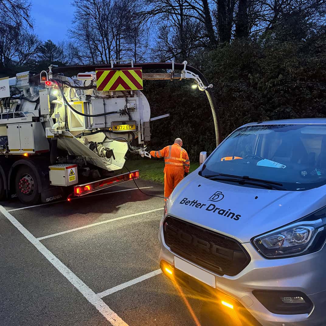 Professional drain cleaning technician using high-pressure equipment on a residential street.